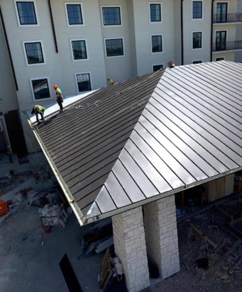 Crew installing standing seam metal roof panels on a commercial project in Robinson